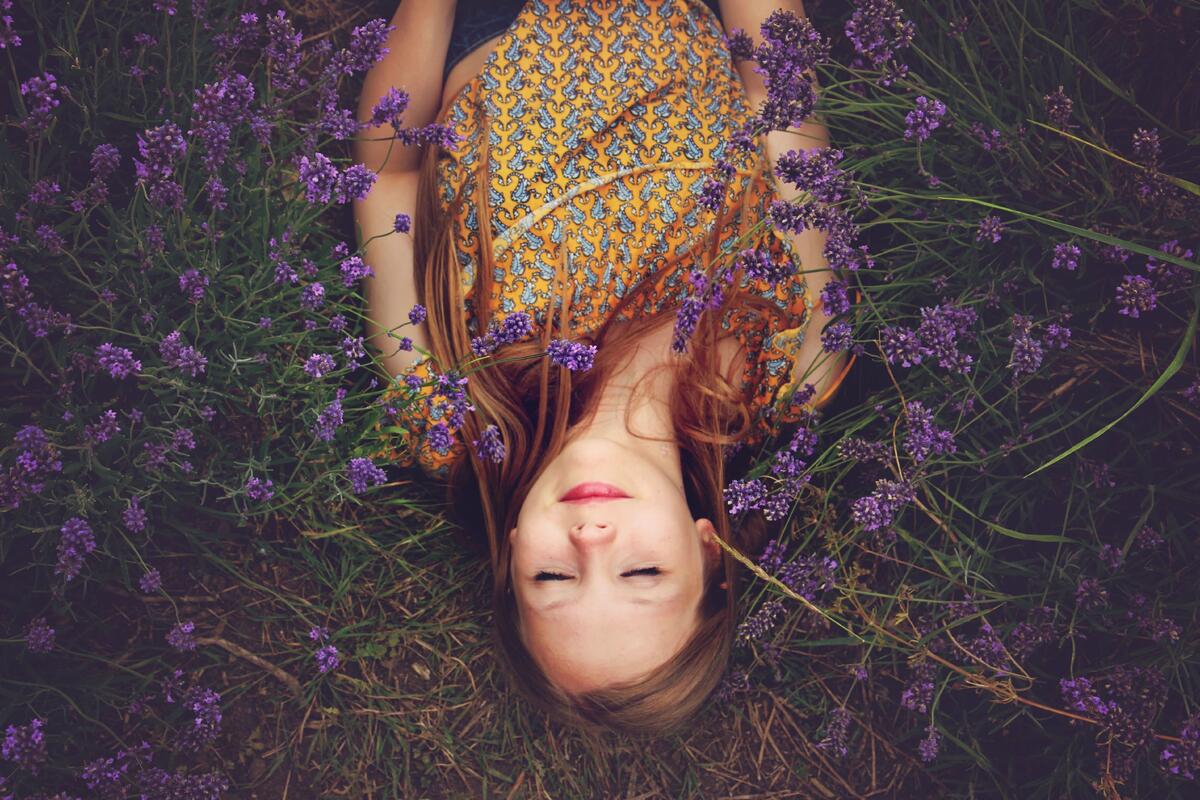 Девушка лежит в поле с фиолетовыми цветами
