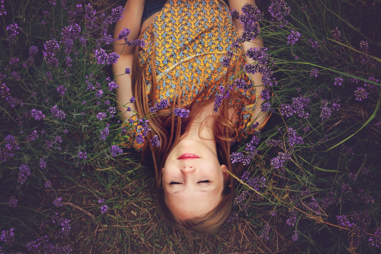 Free photo A girl lies in a field with purple flowers