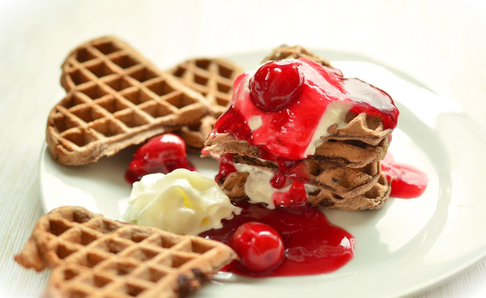 Free photo Delicious waffle hearts with cherry jam