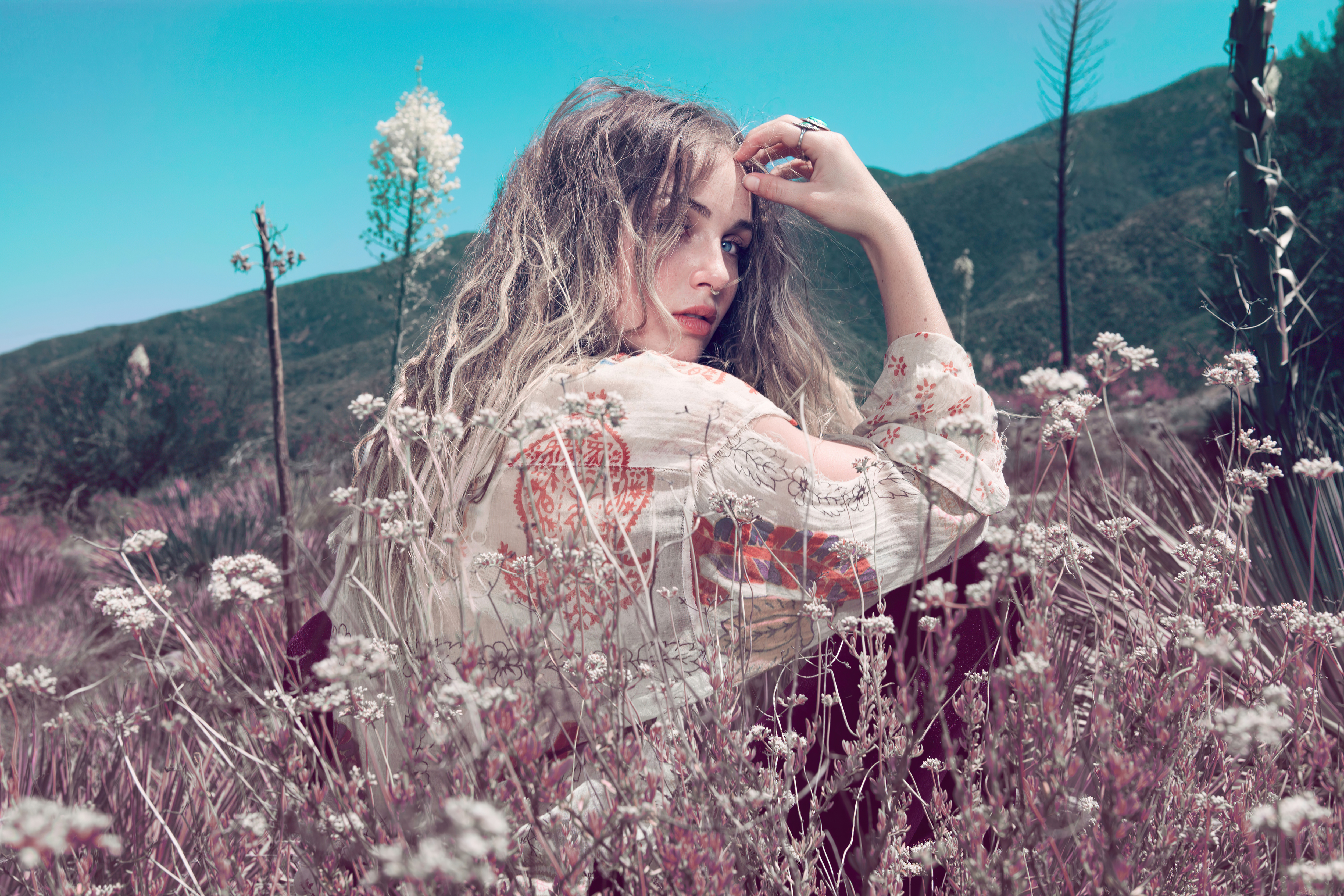 Бесплатное фото Молодая девушка сидит в поле среди цветов