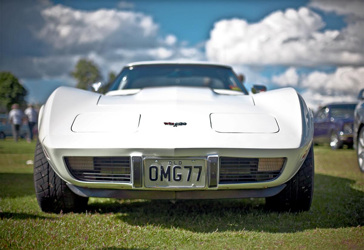 Маслкар Corvette со слепыми фарами в белом цвете на автомобильной выставке