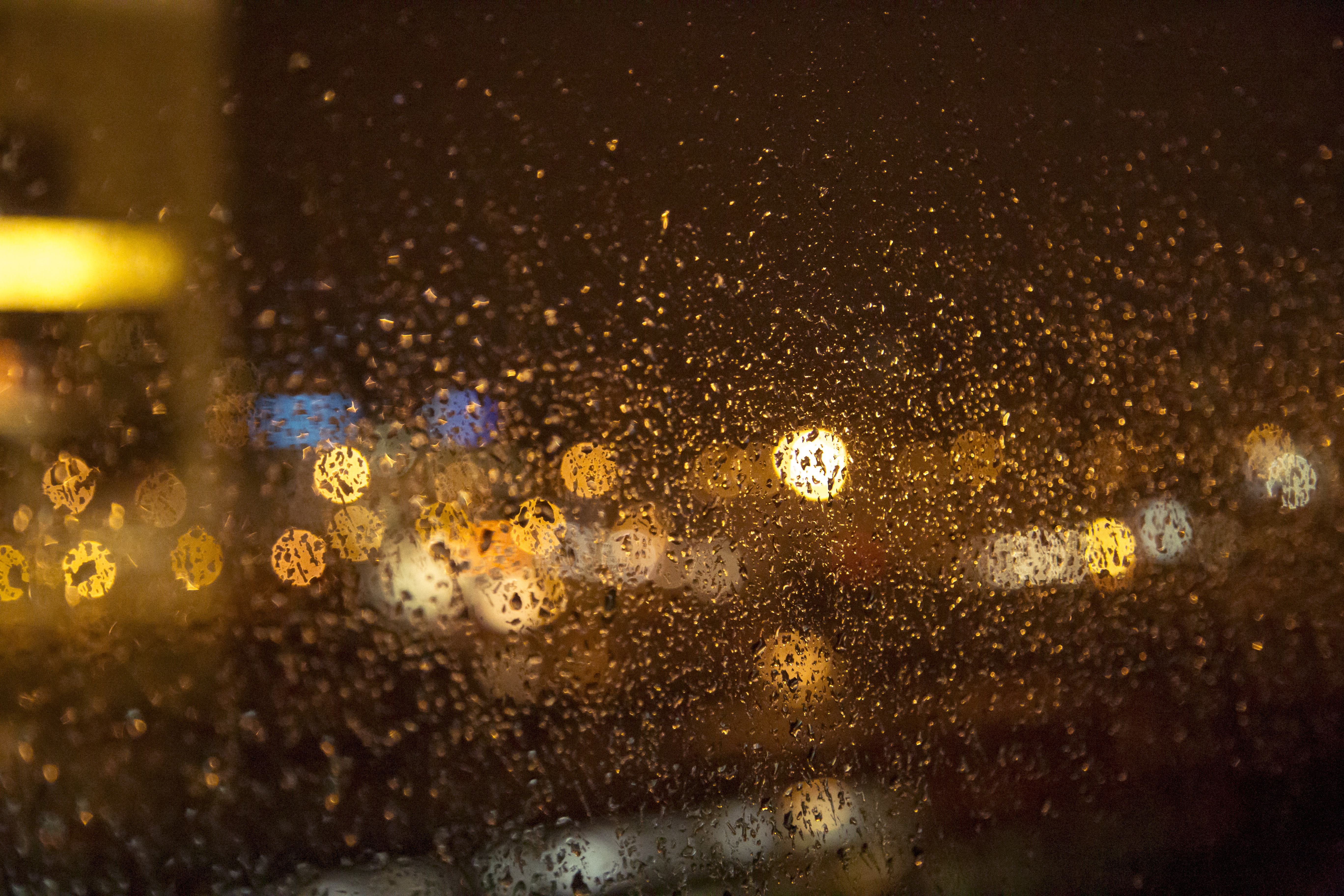 Размытое стекло. Дождь ночью. Капли на стекле машины ночь. Дождливый город за стеклом. Коричневый дождь.