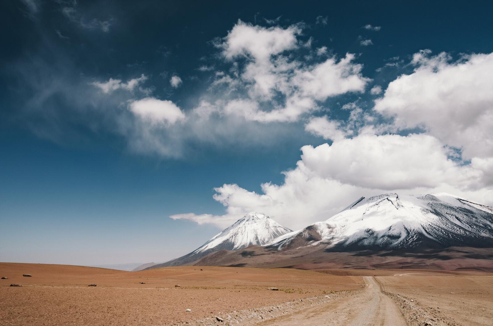 Бесплатное фото Дорога в пустынной местности ведущая к горам с заснеженными холмами