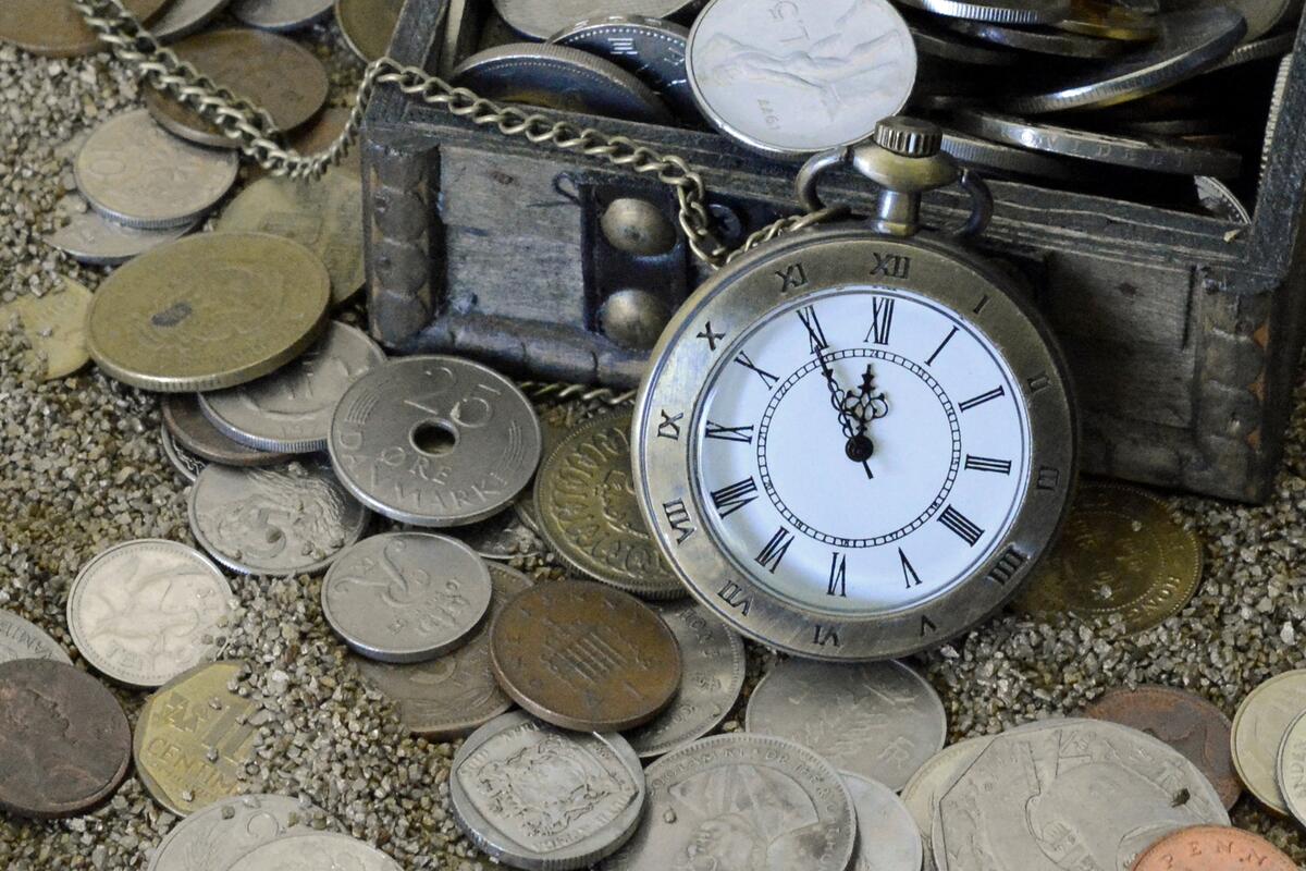Pocket watch with coins in the sand