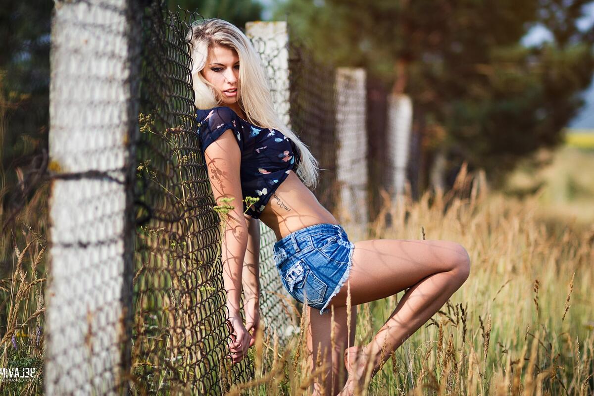 A girl in short jean shorts is standing at the fence