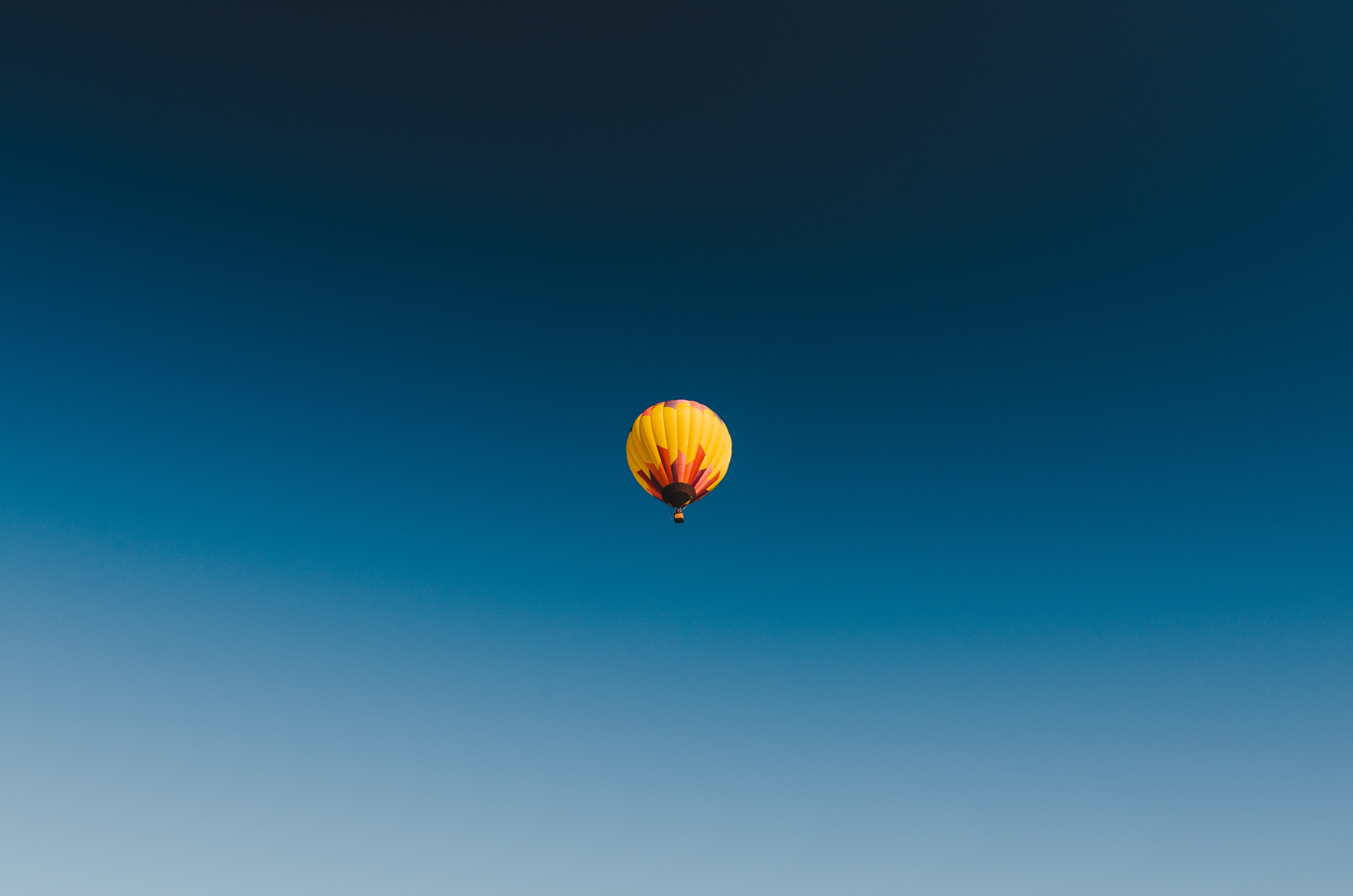 黄红相间的气球在蓝天下飘荡