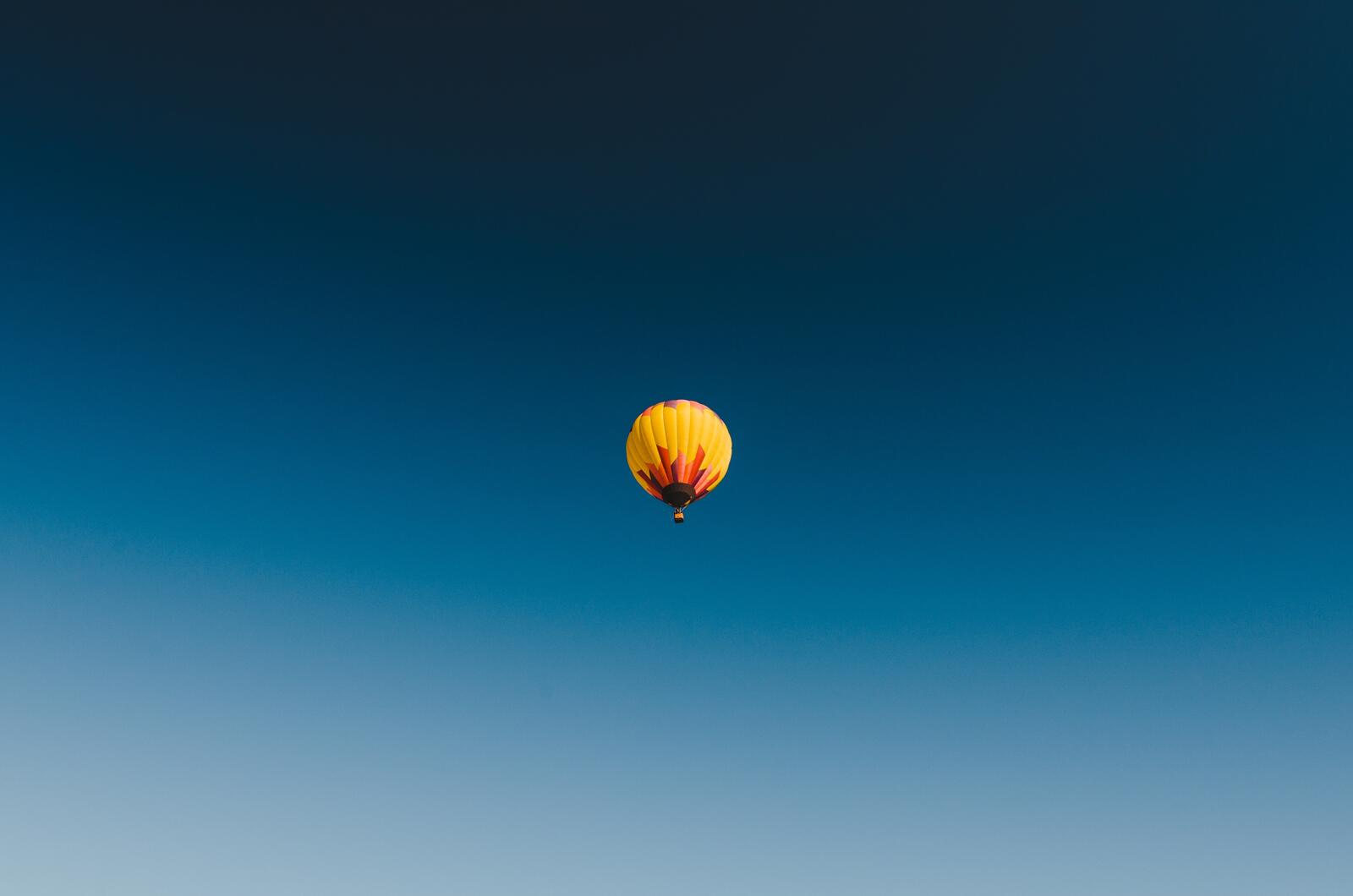 Free photo A yellow and red balloon floats against the blue sky