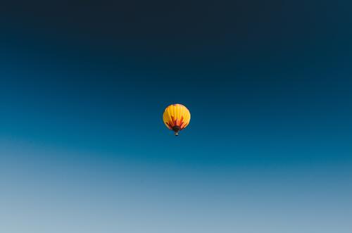 Жёлто-красный воздушный шар парит на фоне синего неба