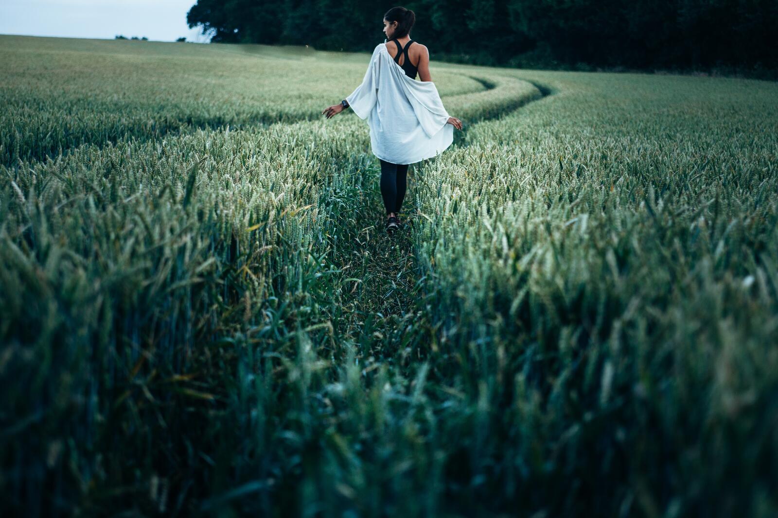 Free photo A girl walks through a field of tall grass.