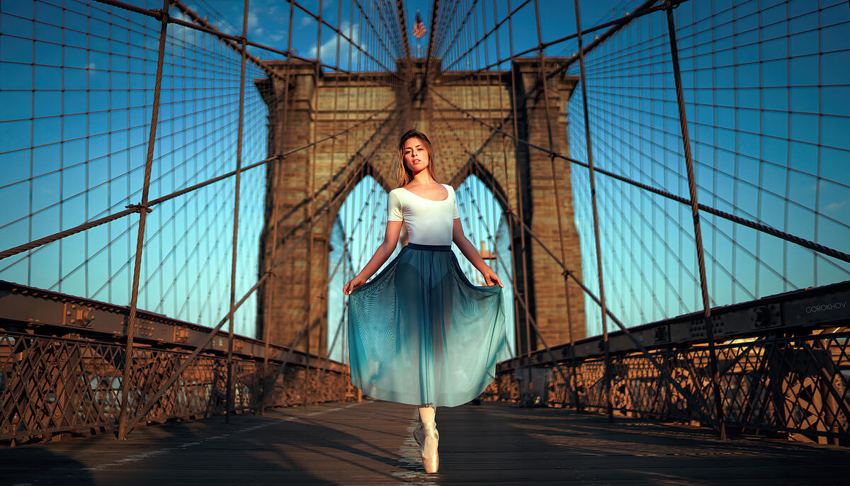 A girl in a light dress poses on a large pedestrian bridge
