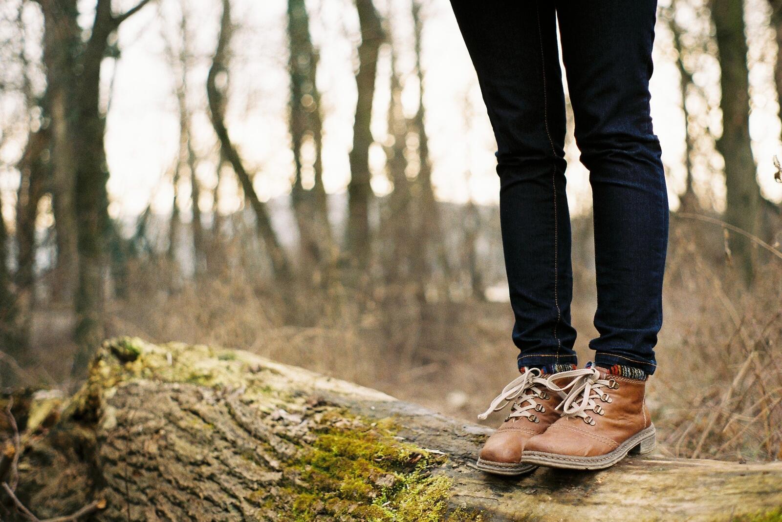Free photo A man standing in brown leather boots on a fallen tree