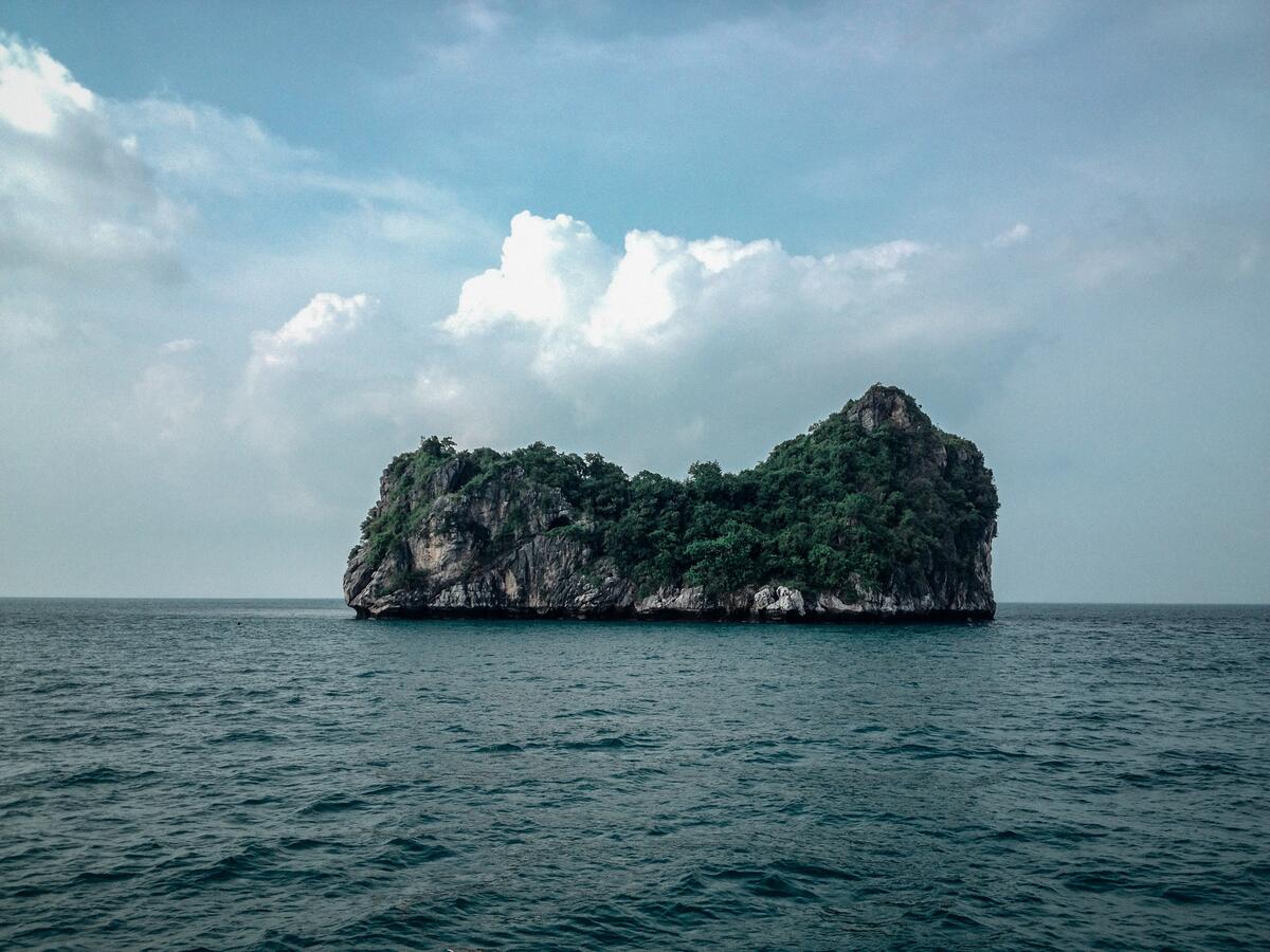 An island in the middle of the sea in the form of a rock with trees on it