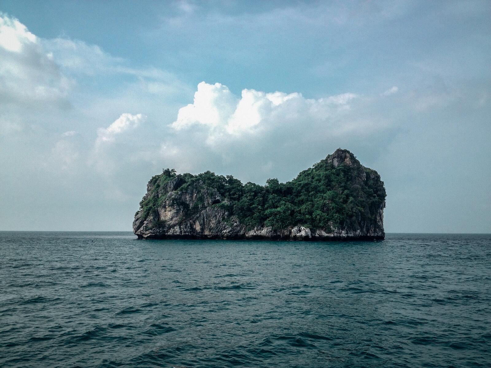 Бесплатное фото Остров среди моря в виде скалы с деревьями на ней