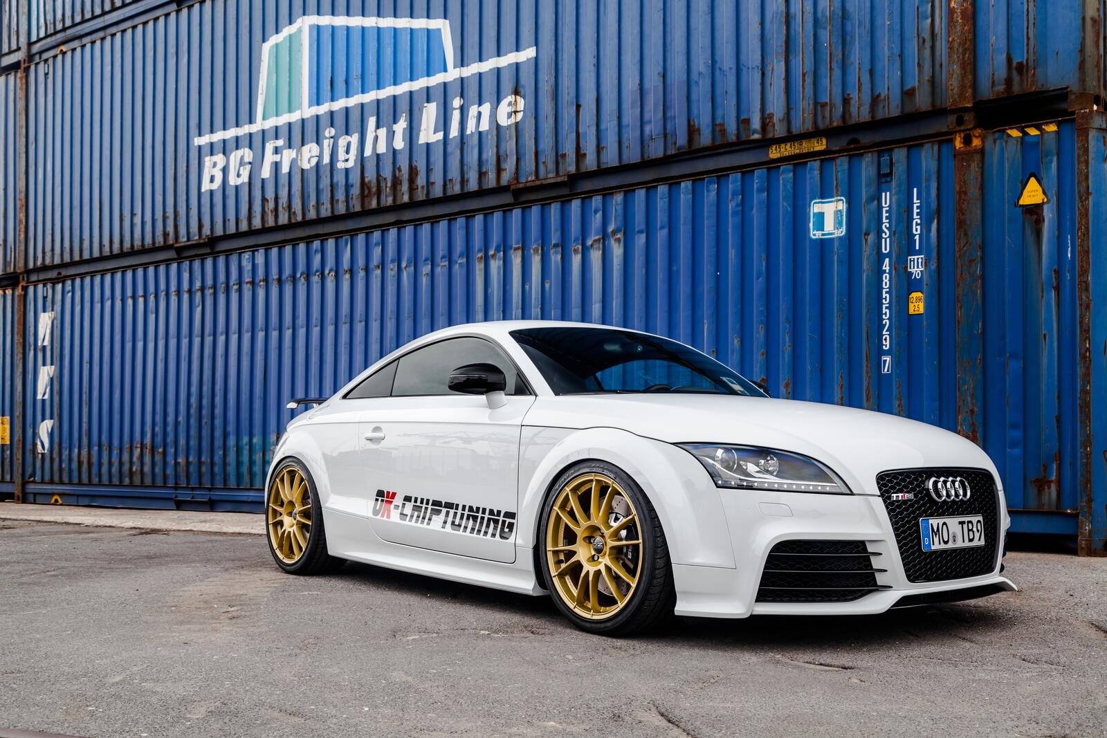 Free photo A white Audi TT against a backdrop of containers