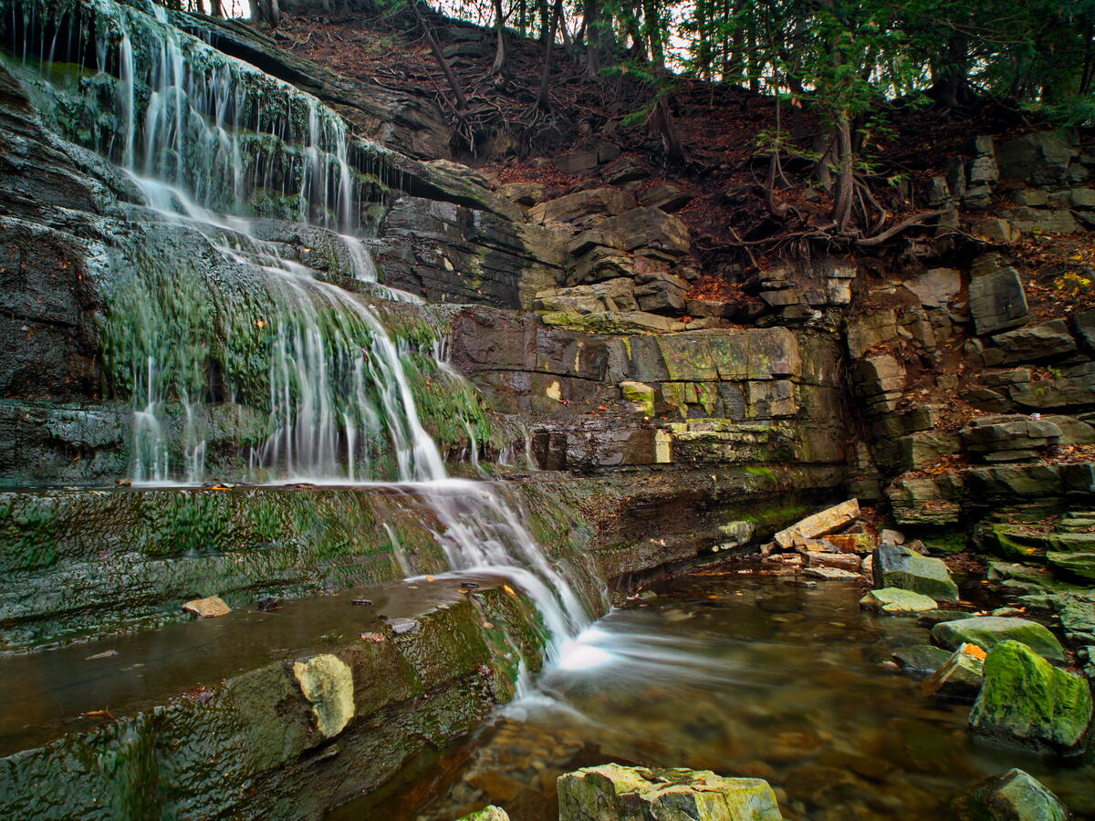 A picture of a multi-story waterfall in the woods