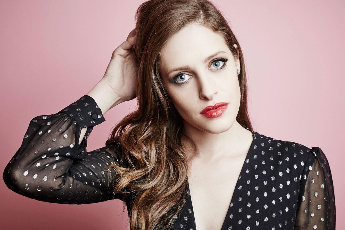 A portrait of Carly Chaikin on a pink background