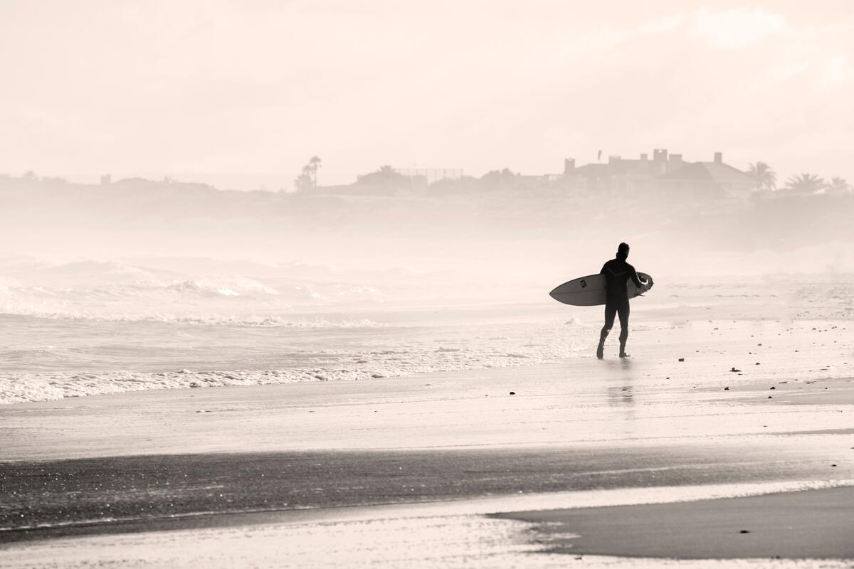 A surfer walks along the shore
