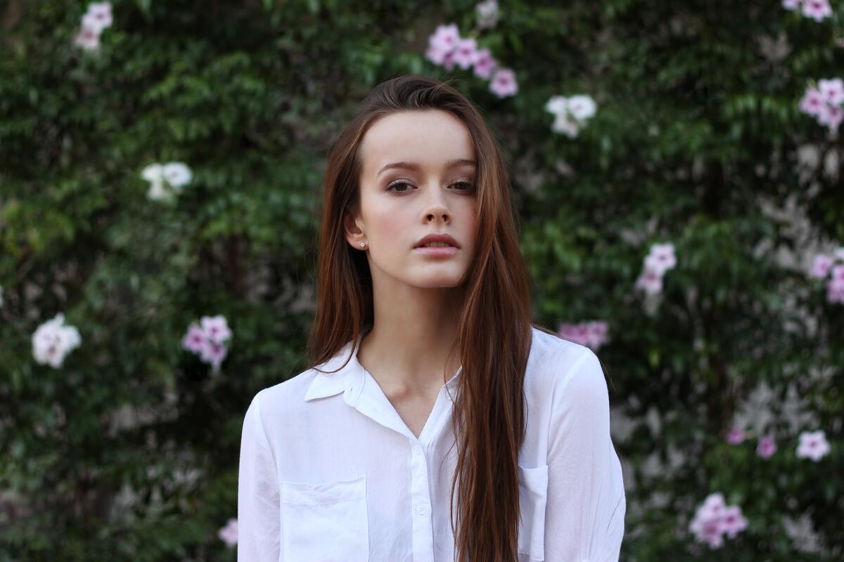 A girl in a white shirt against the background of a flowering tree