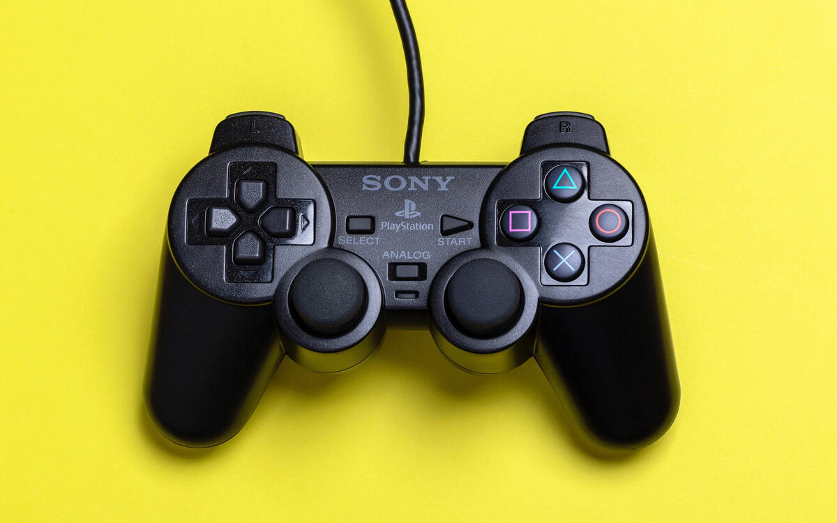 Джойстик PlayStation на желтом фоне