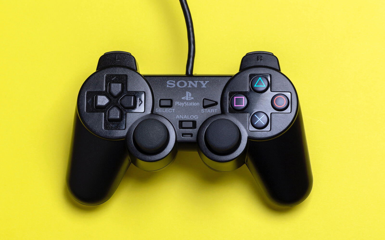 Бесплатное фото Джойстик PlayStation на желтом фоне