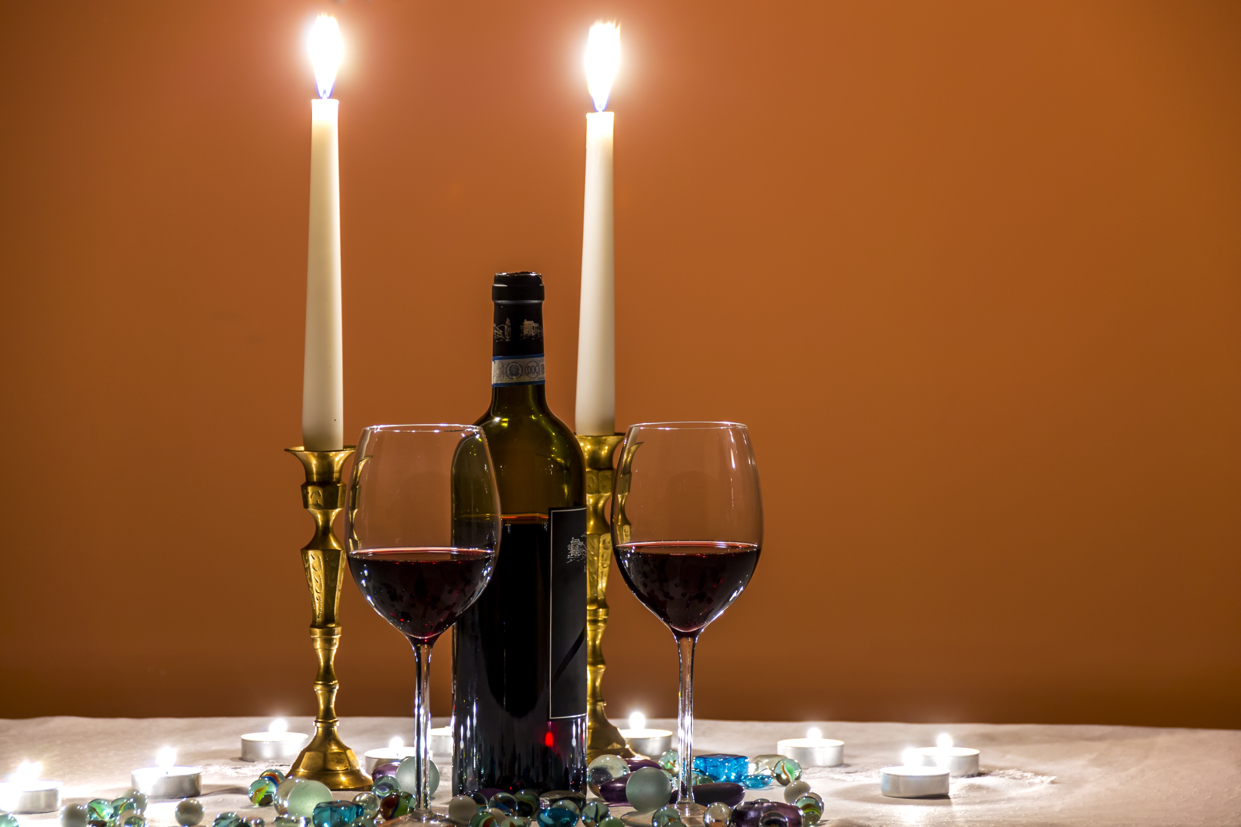 Two glasses of red wine with candles burning.