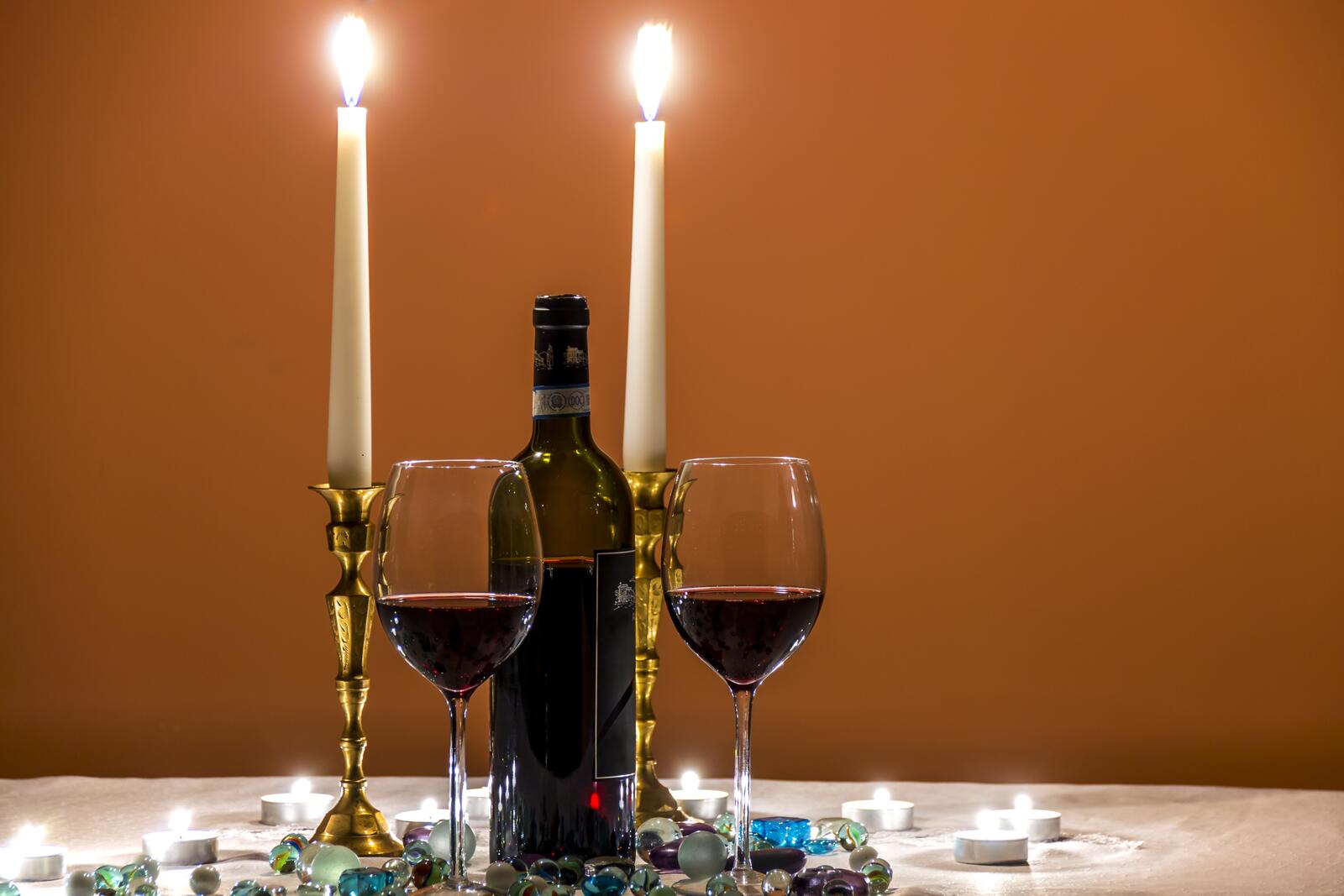 Free photo Two glasses of red wine with candles burning.