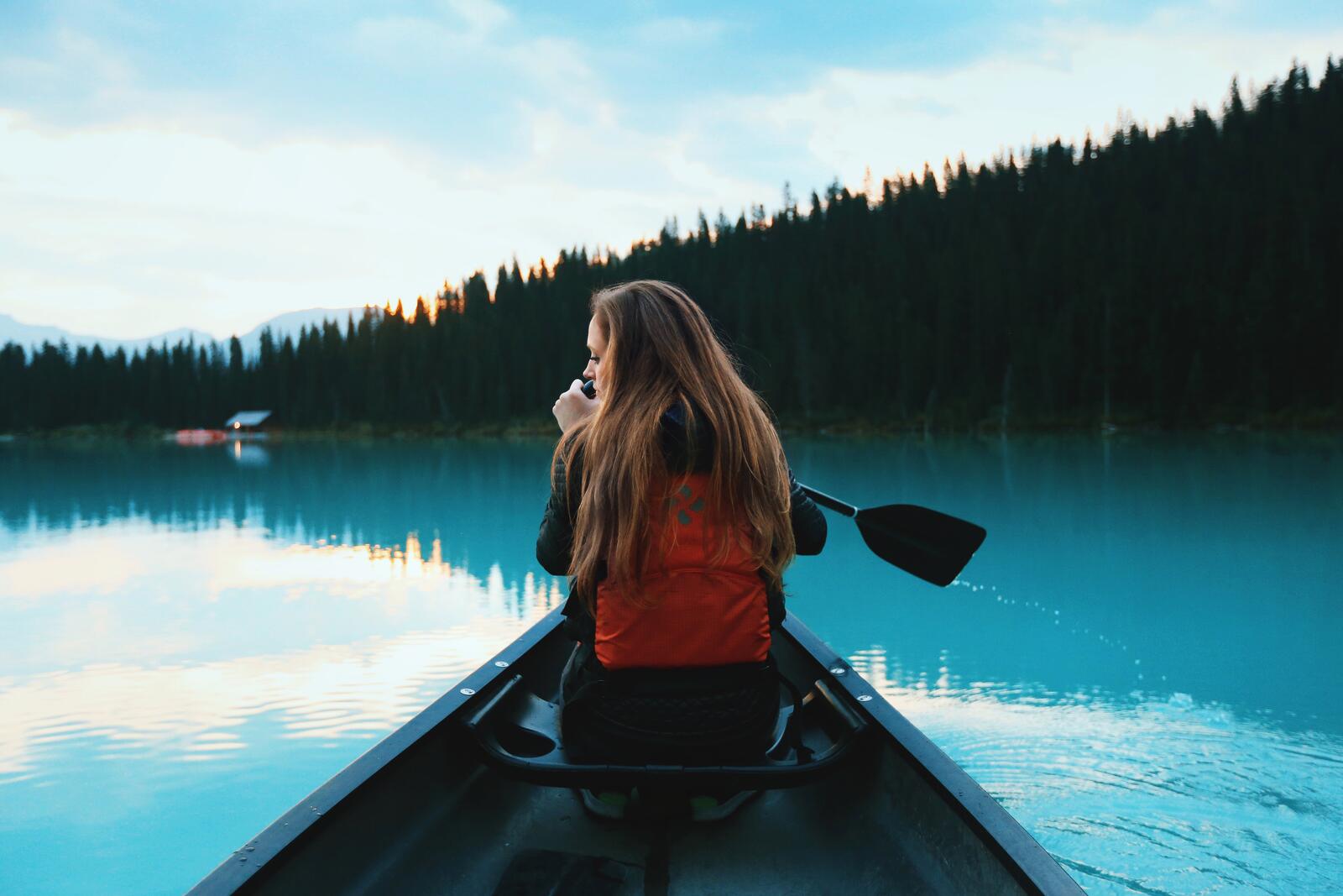 免费照片一个女孩划着独木舟漂浮在湖面上。