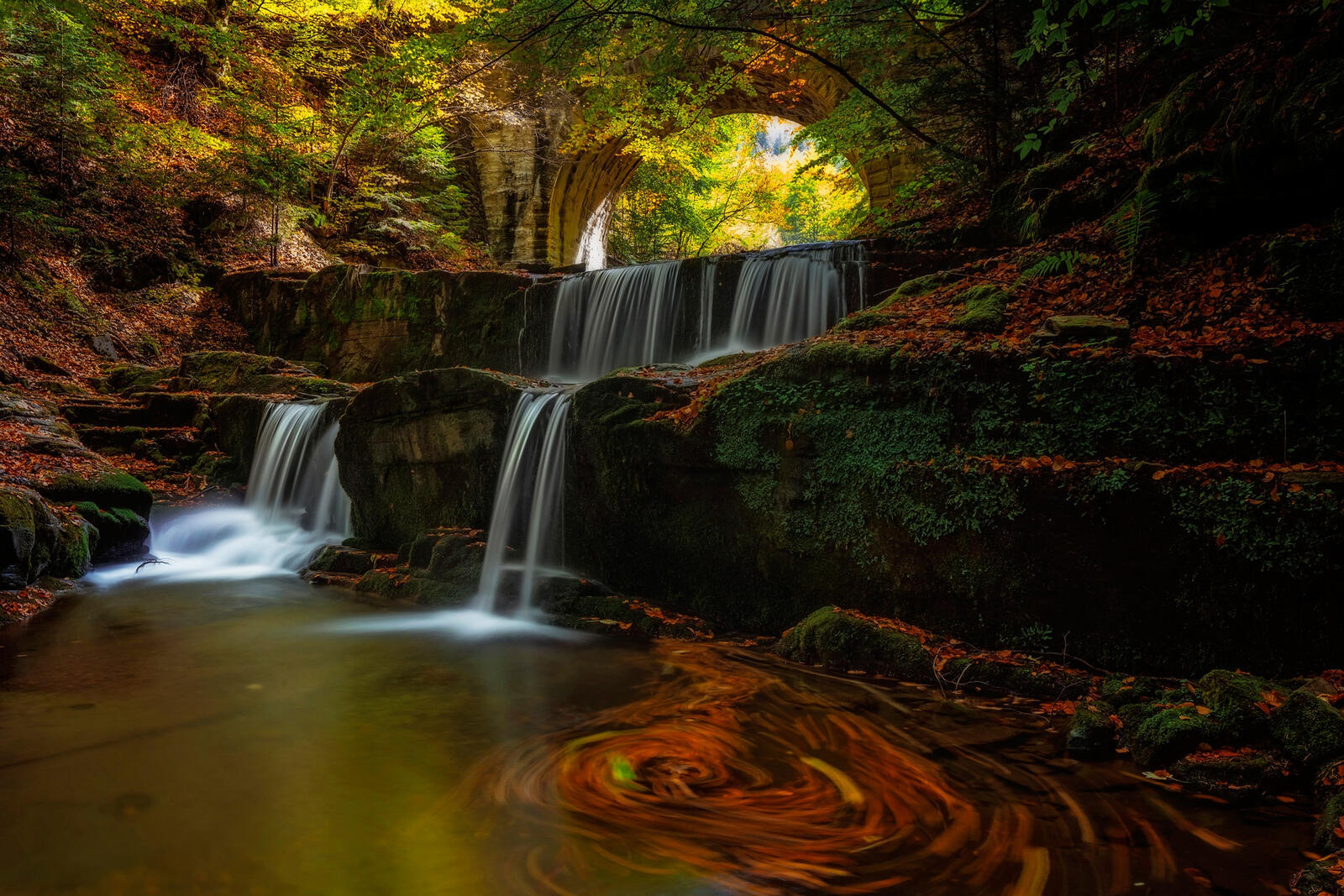 Free photo A waterfall with an arch in the fall woods