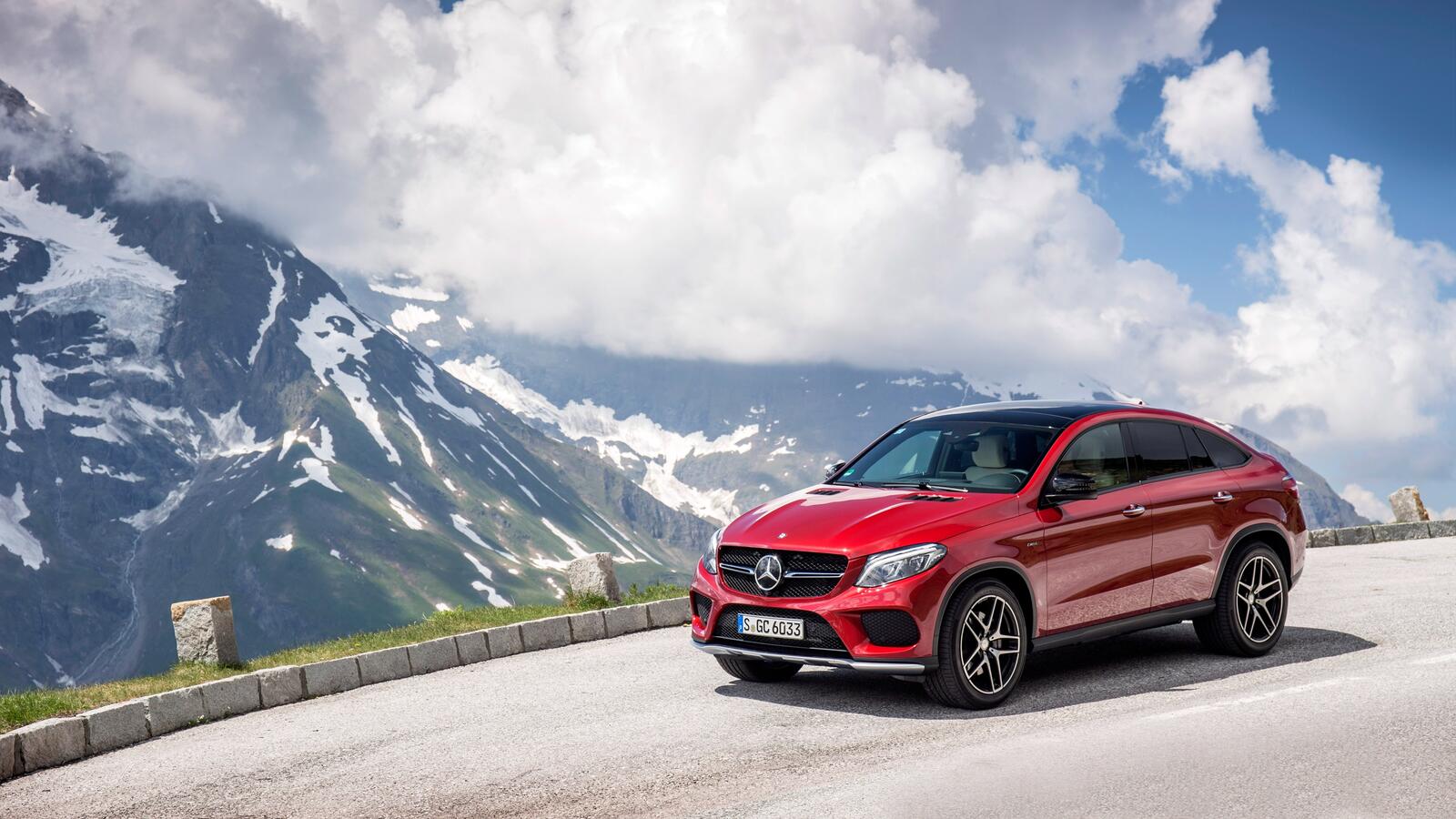 Free photo A red Mercedes Benz gle 450 against a backdrop of snowy mountains.