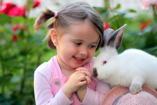 A little girl playing with a fluffy rabbit.