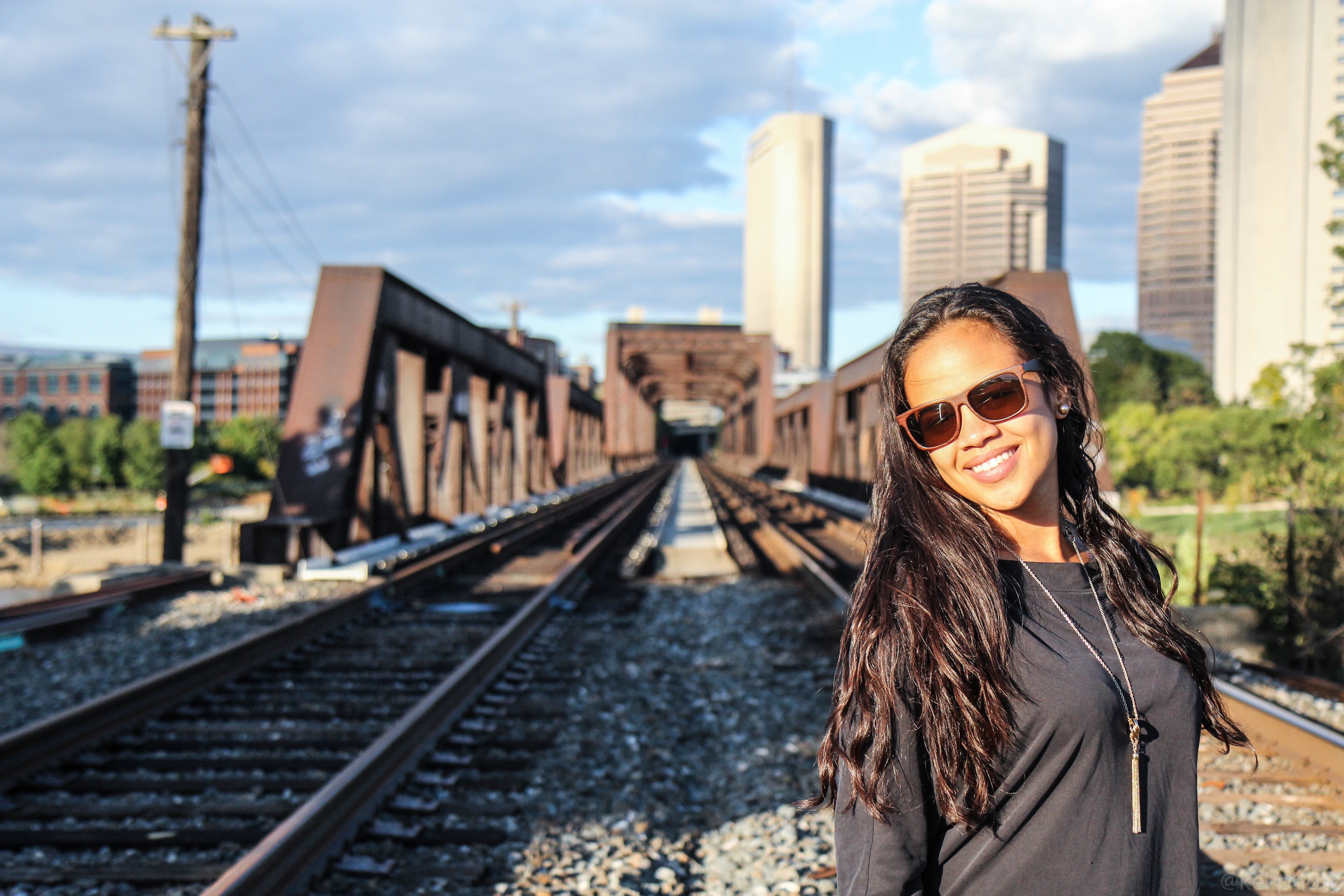 Чернокожая девушка в солнечных очках на фоне железной дороги