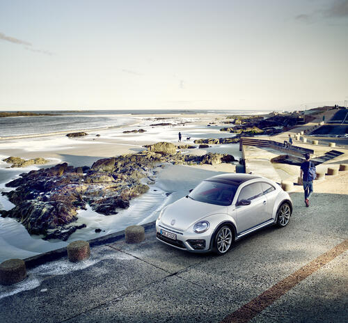 Silver volkswagen beetle stands on the bridge near the sea shore
