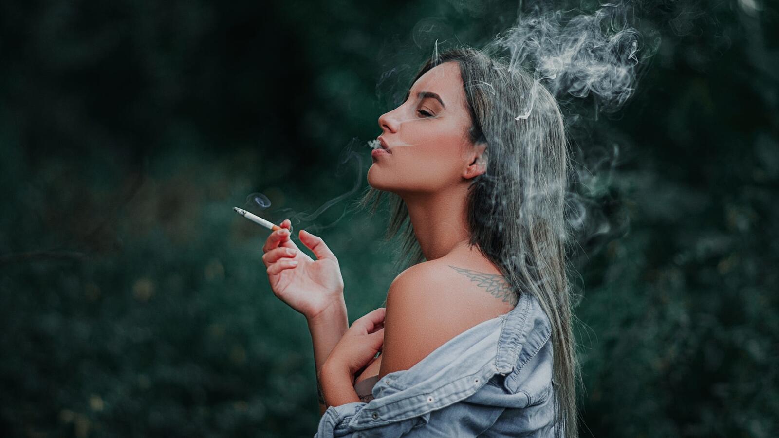 免费照片吸烟的黑发女孩，背上有纹身。