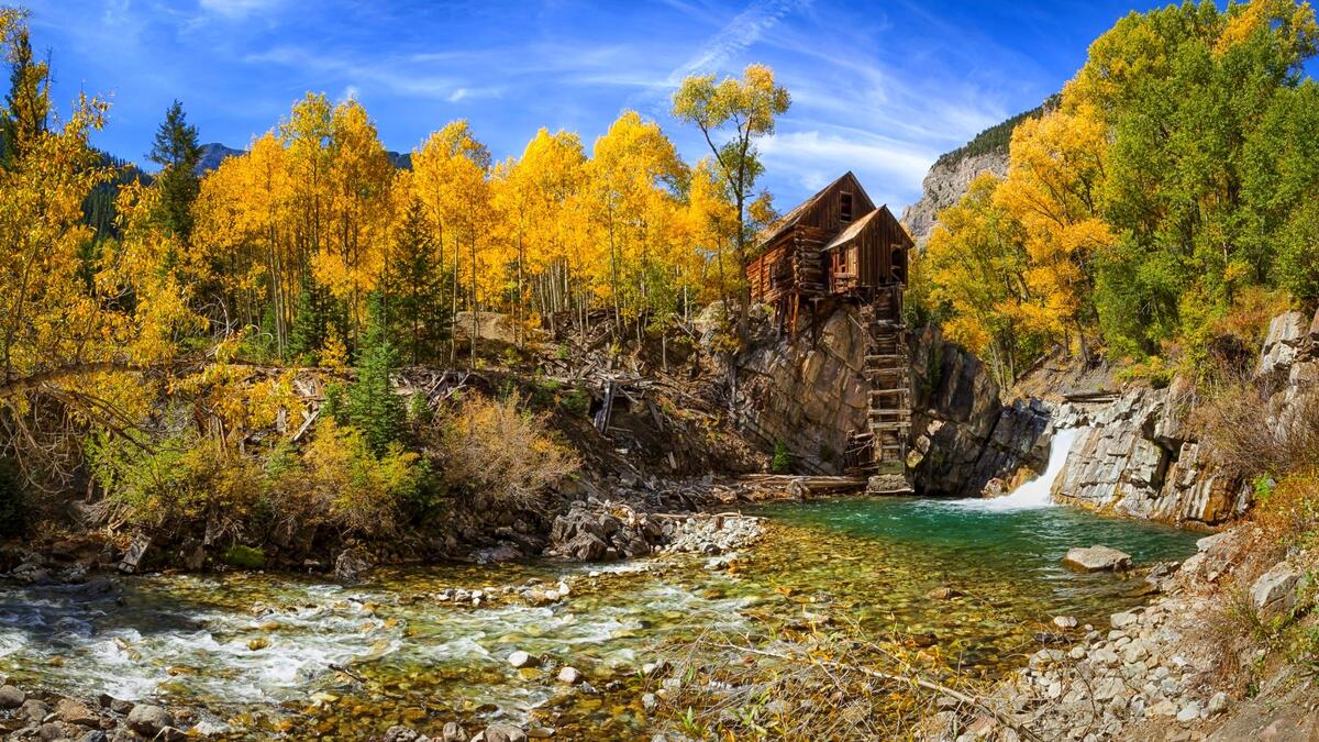 Деревянный дом на скале в осеннем лесу у реки