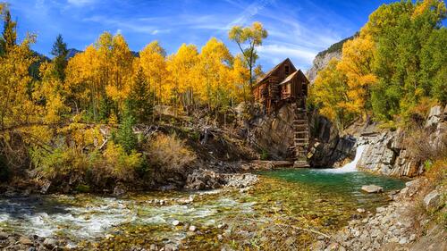 Wooden house on a cliff in the fall forest by the river