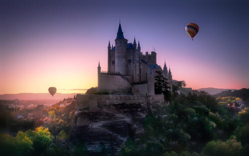 Balloons fly over an ancient castle on a cliff top