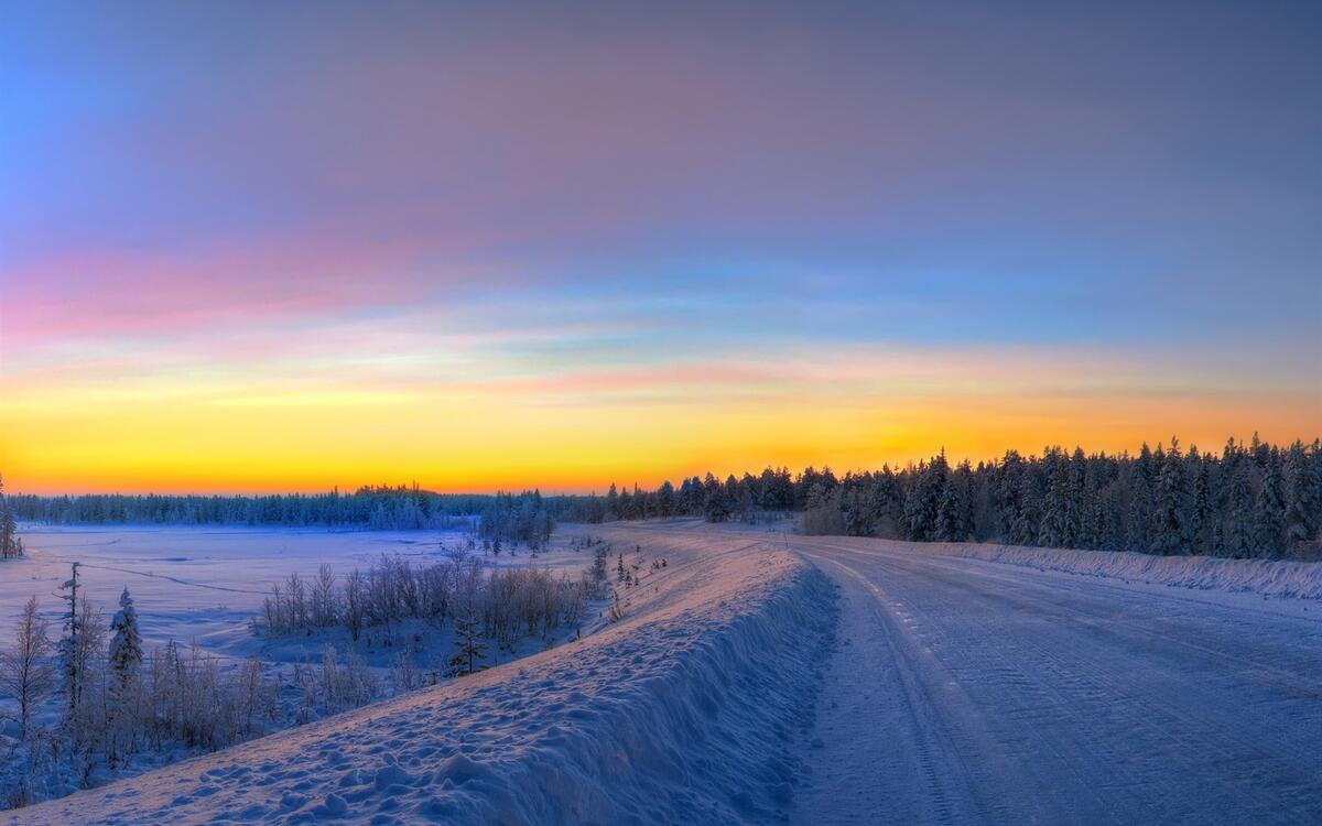 Зимняя дорога в сугробах на рассвете дня