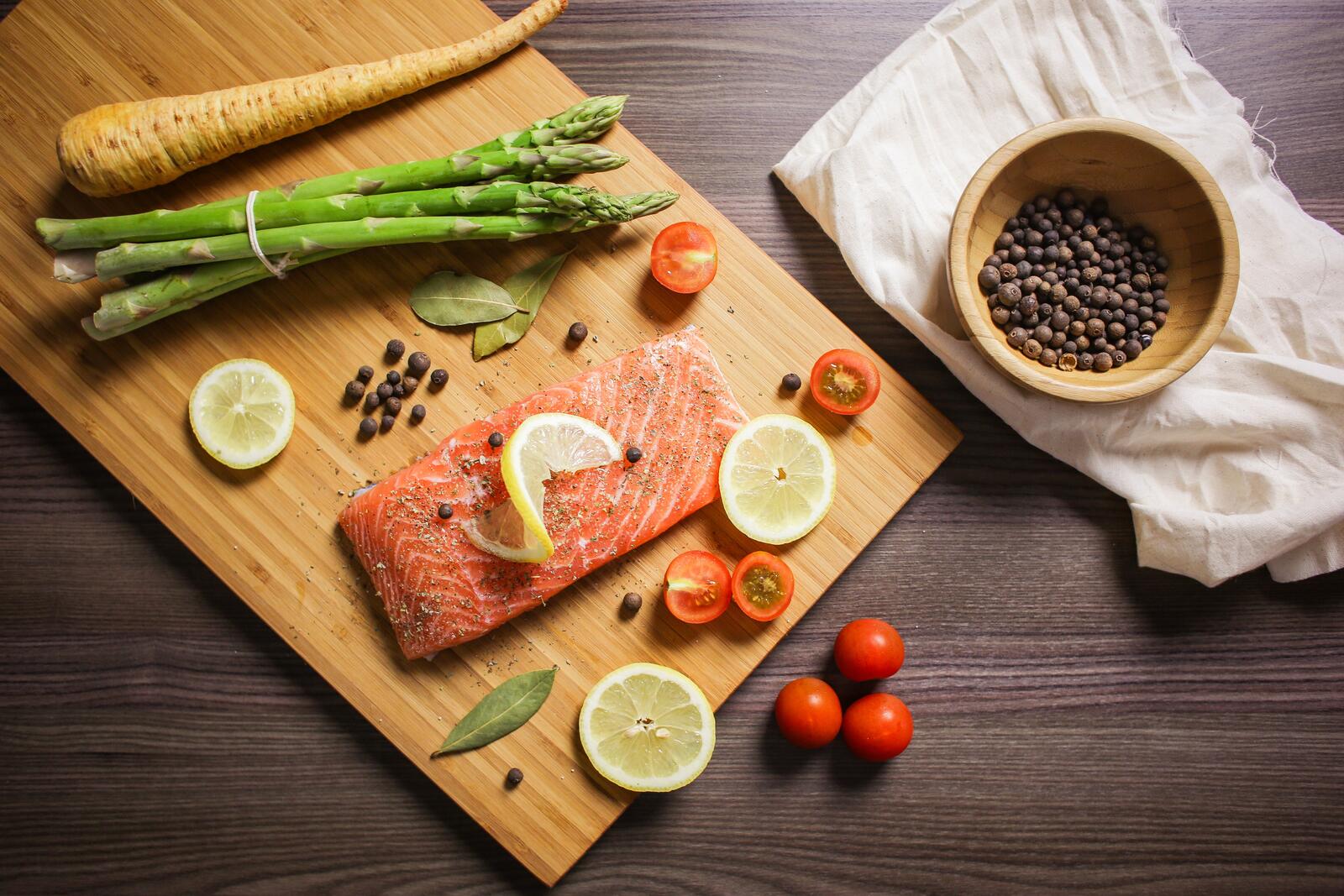 Бесплатное фото Красная рыба лежит на деревянной доске с овощами
