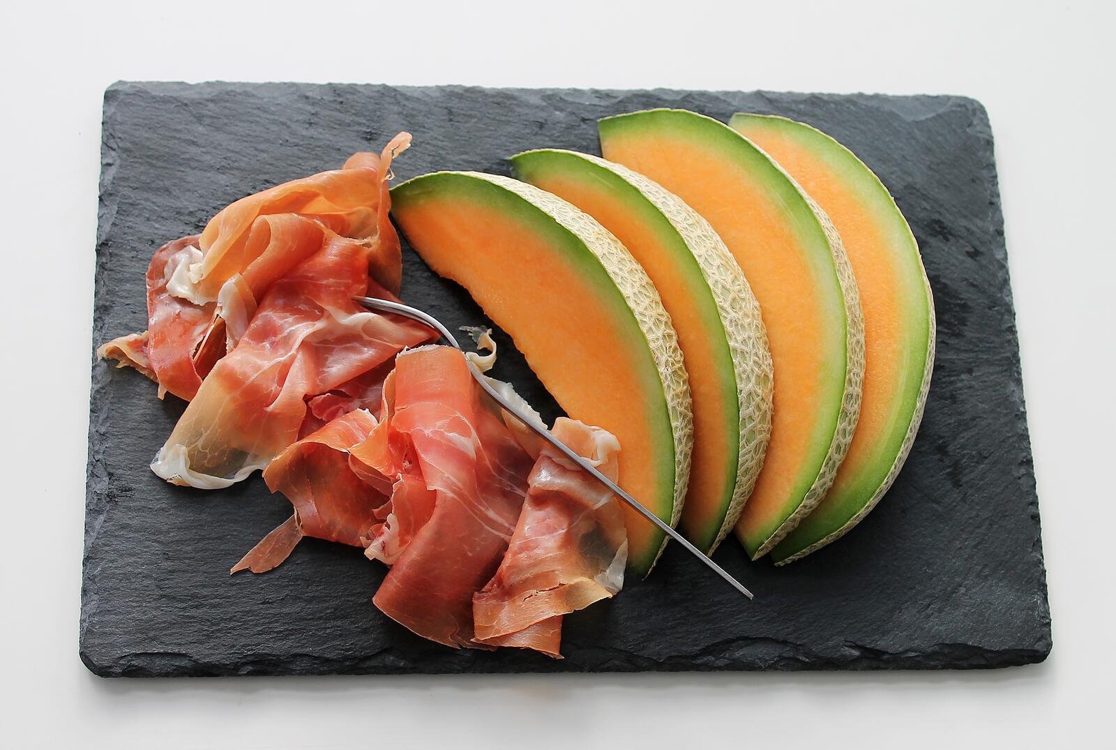 Free photo Melon slices with thin slices of bacon