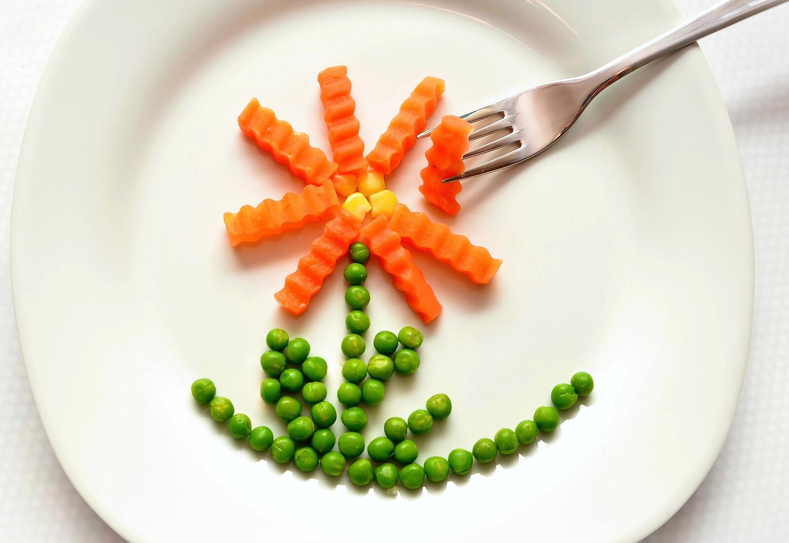 Free photo A palm tree of carrots and peas on a white plate