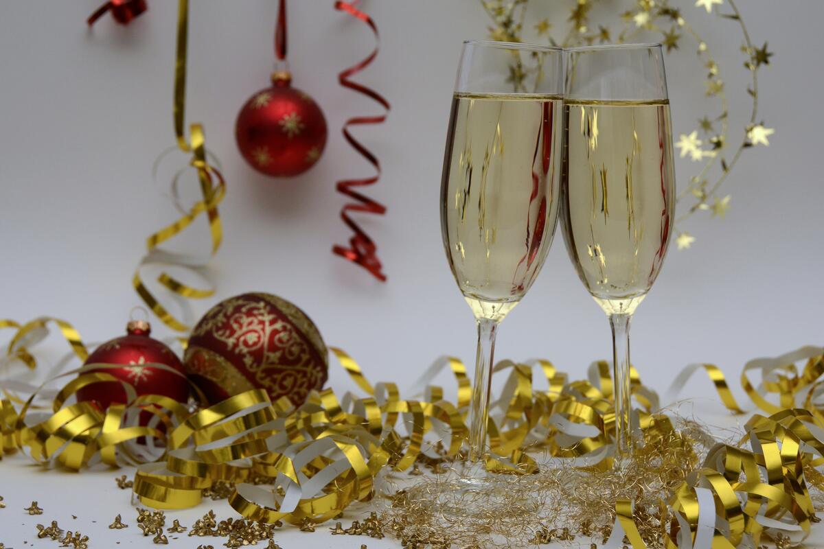 Два бокала новогоднего шампанского на фоне серпантина и игрушек