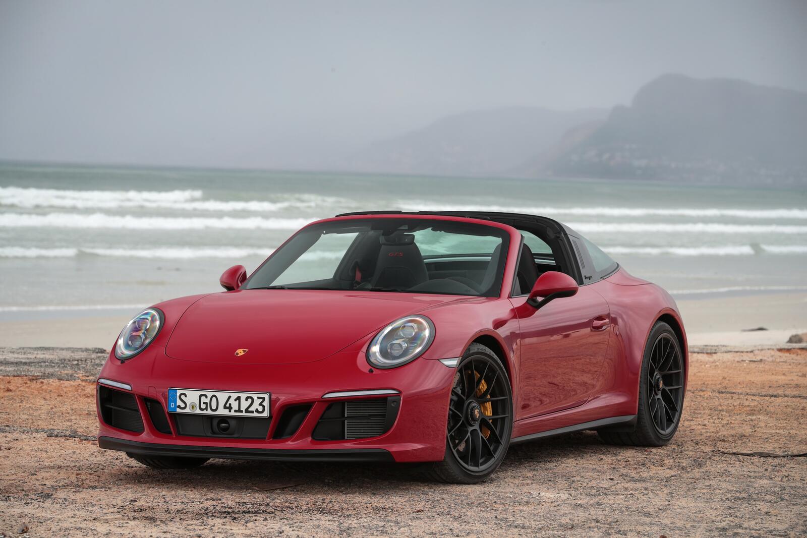 Free photo A red porsche 911 targa stands on a beach by the sea