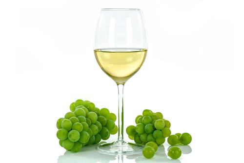A glass of wine with a bunch of grapes.