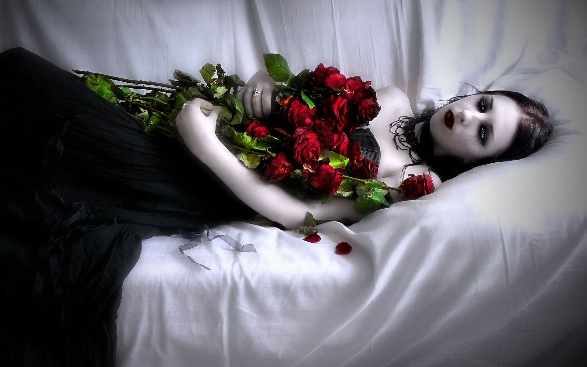 A pale girl lying on the couch with a bouquet of red roses
