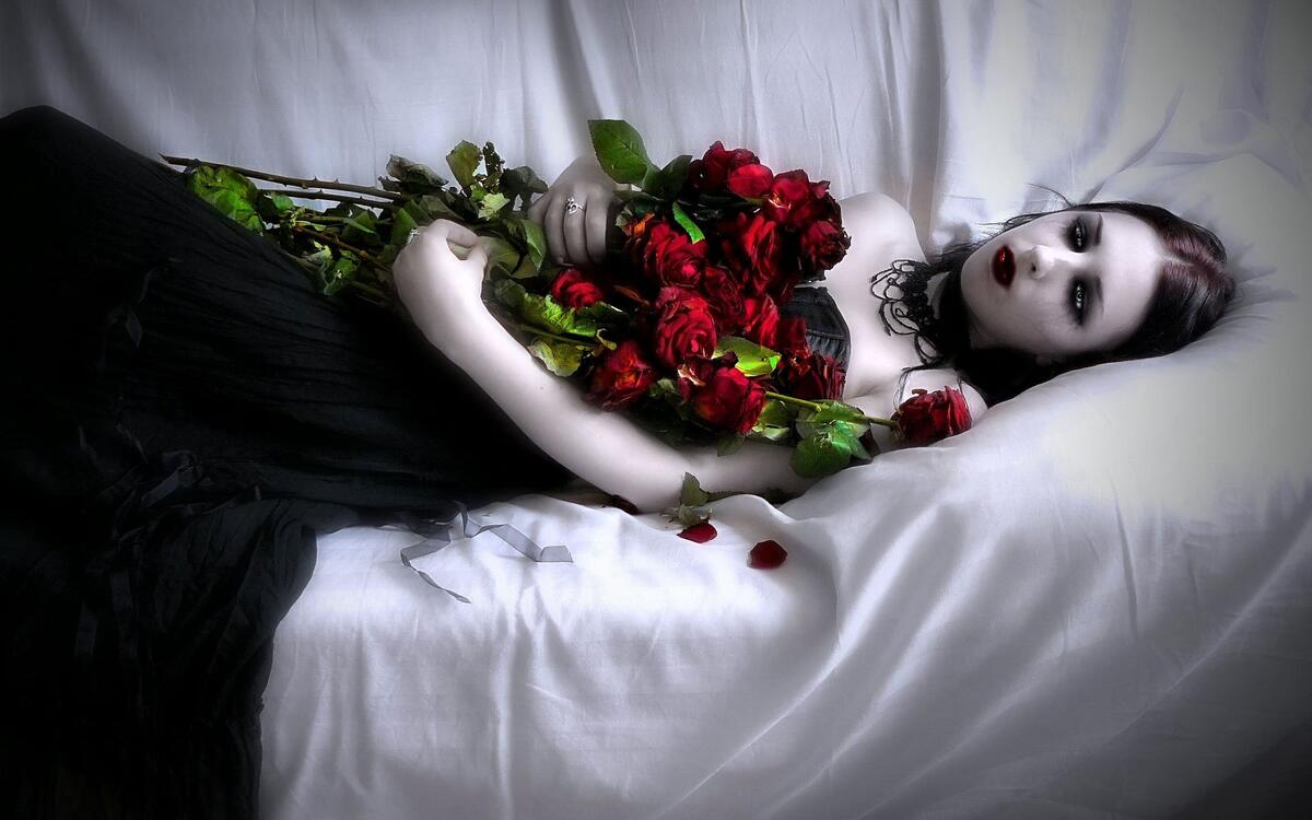 Бледная девочка лежит на диване с букетом красных роз
