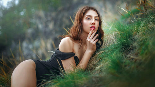 Красивая девушка с красными губами позирует в траве