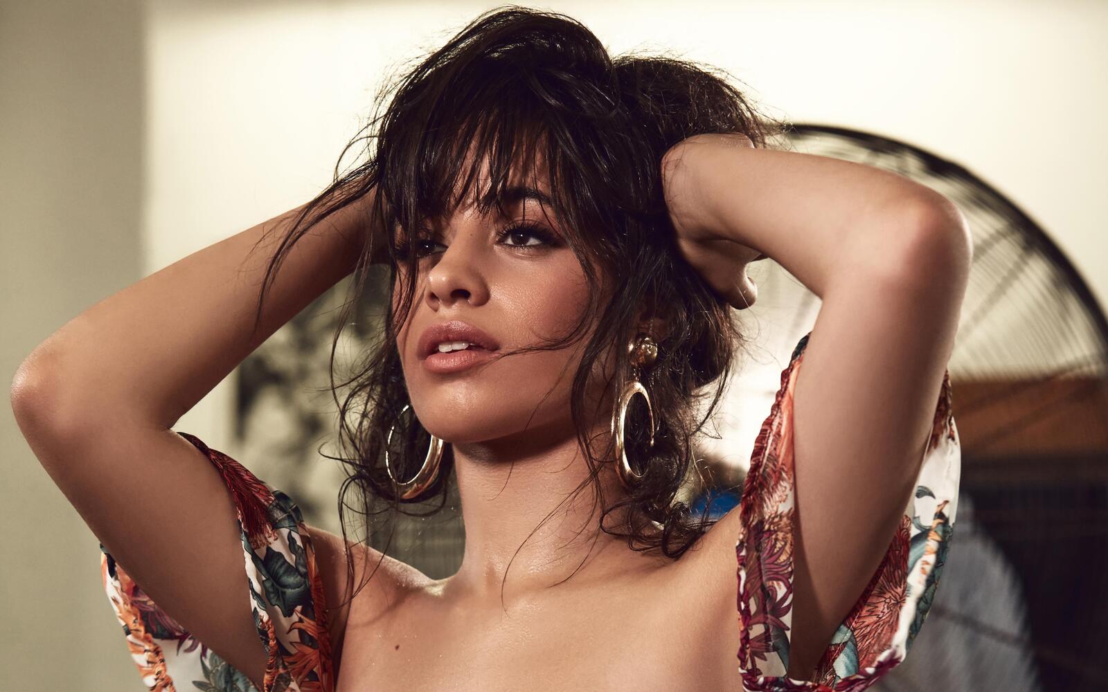 Free photo Camila Cabello holds her hands behind her head and looks into the distance
