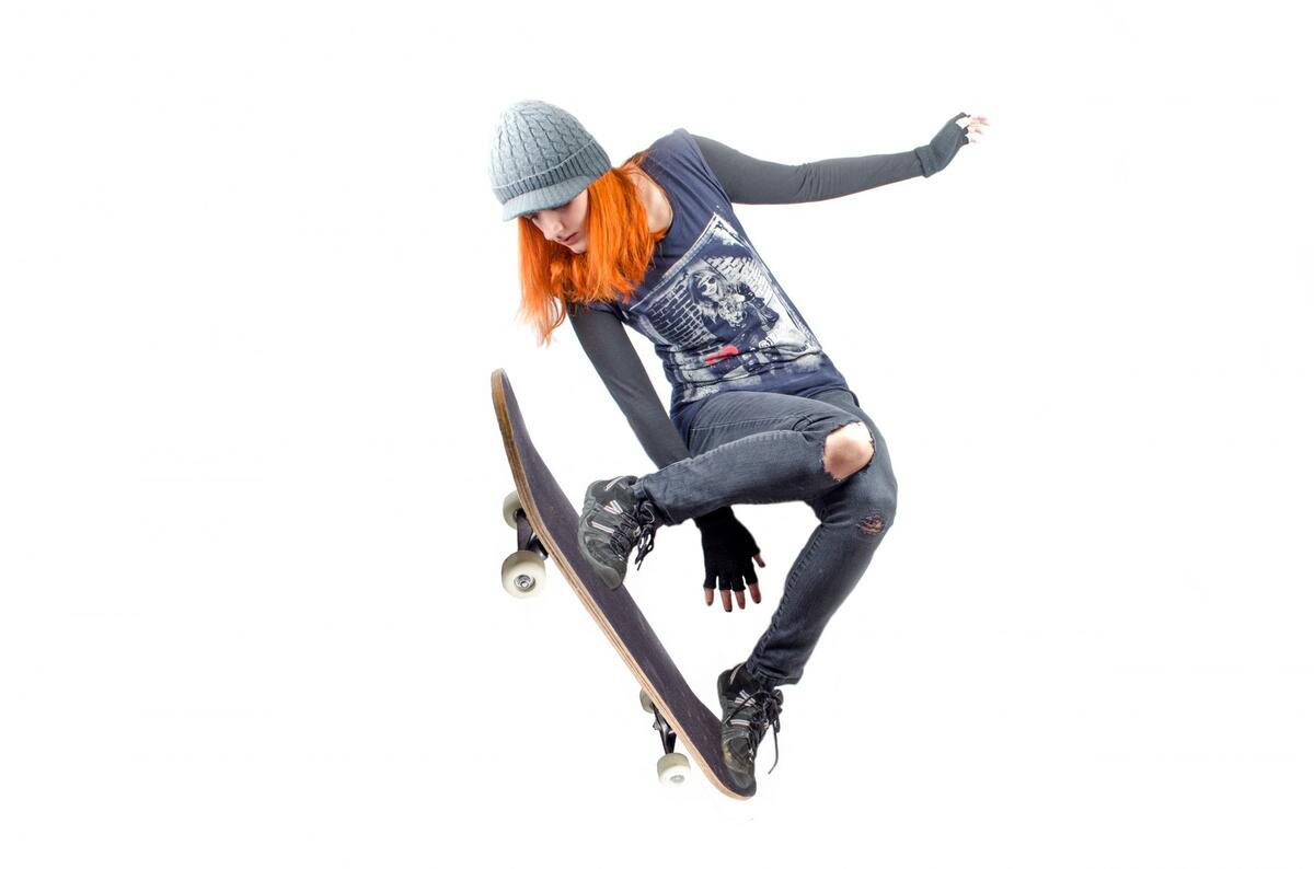 A girl with red hair jumps on a skateboard