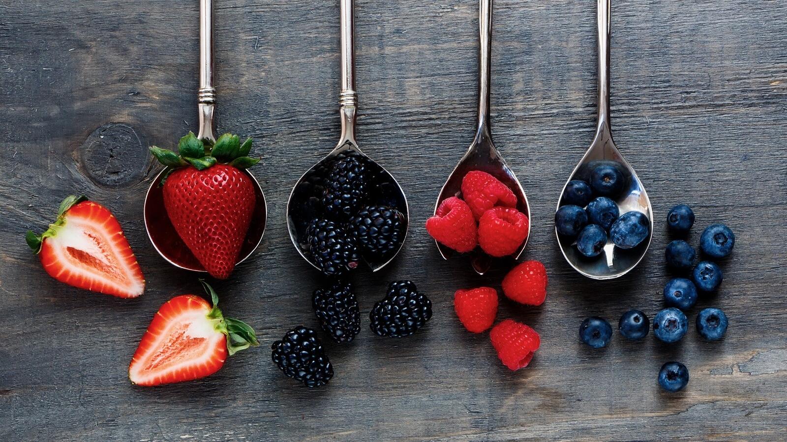 Free photo Spoons on the table with an assortment of berries