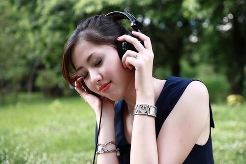一位亚洲女孩戴着耳机听音乐